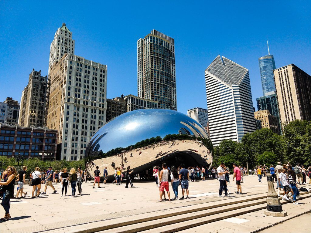 tourists crowd around and take selfies at the bean AKA cloud gate