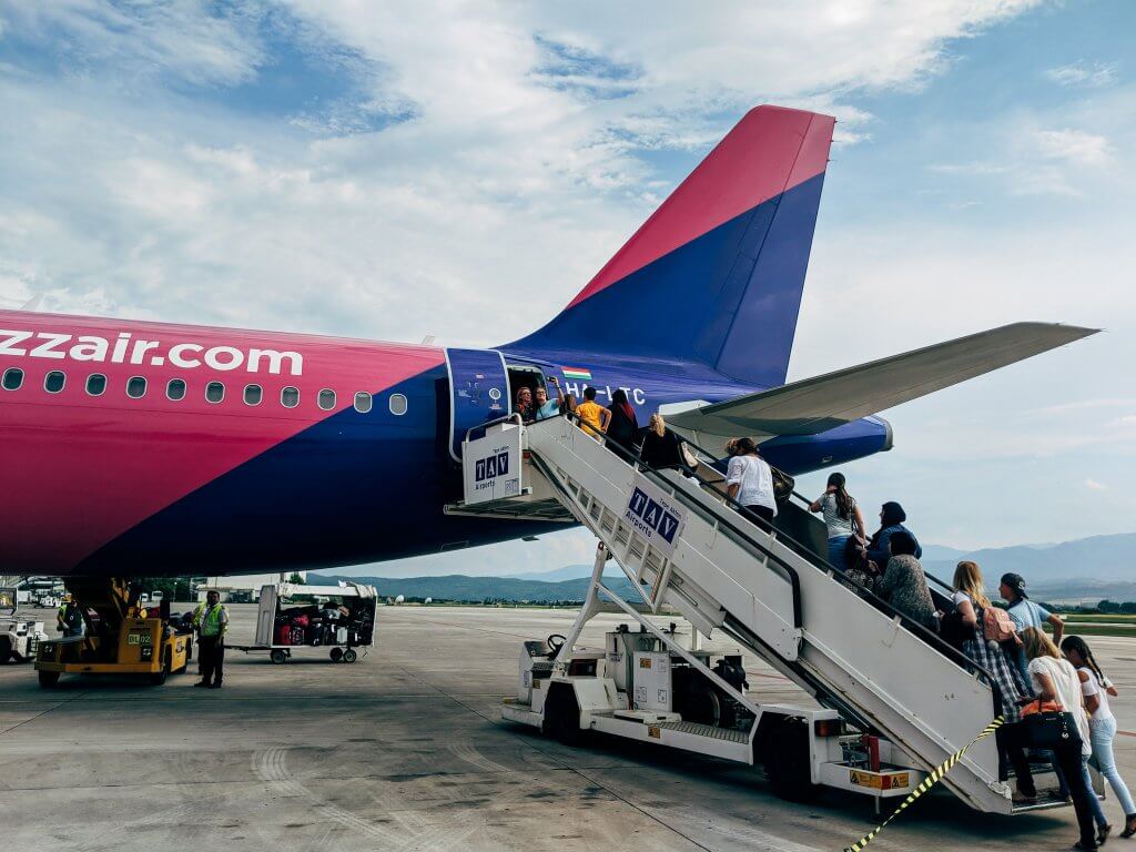 people walking up stairs to board the back entrance of a plane