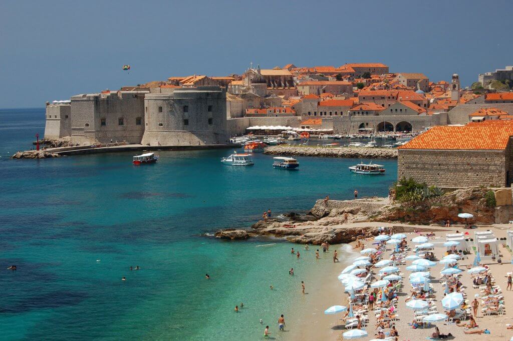 People enjoying the beach in Dubrovnik with the city in the background