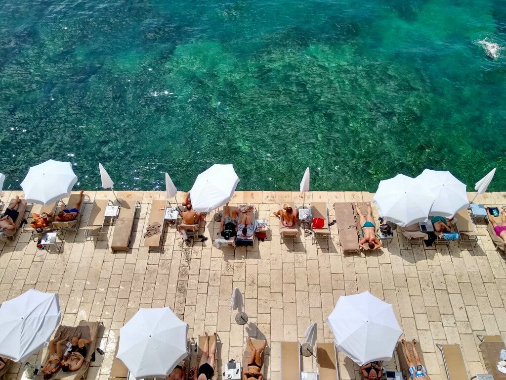 aerial shot of sunbathers underneath umbrellas in Croatia