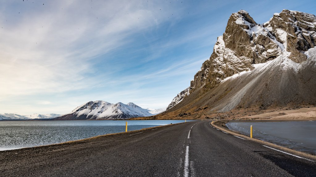 road flanked by water on both sides with a mountain up ahead