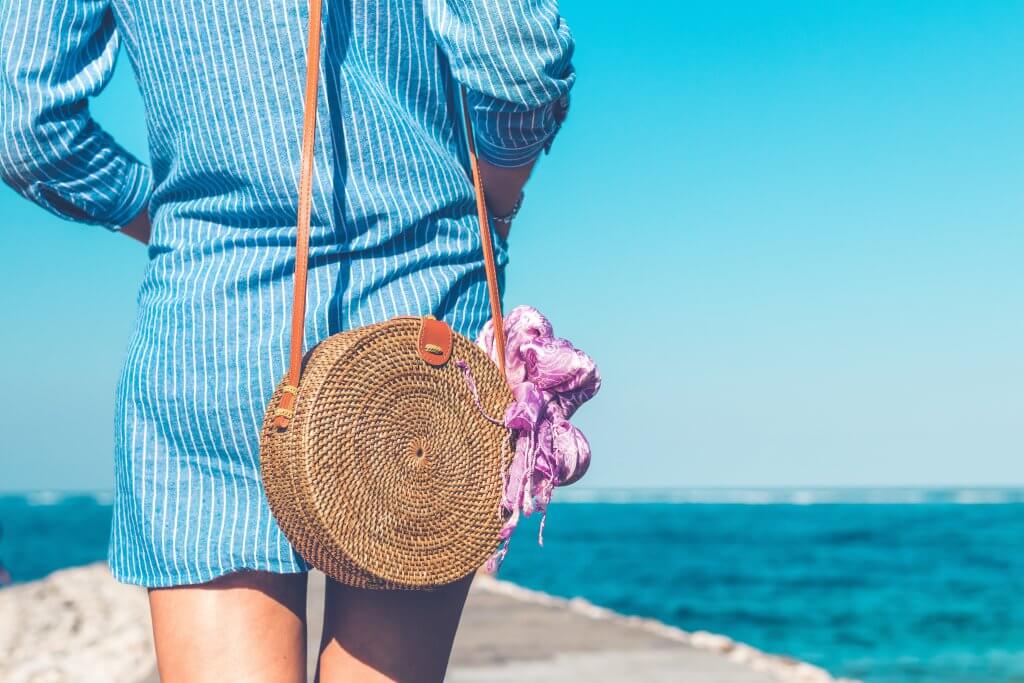 view from the back of a woman from the elbows down with a focus on a rattan bag